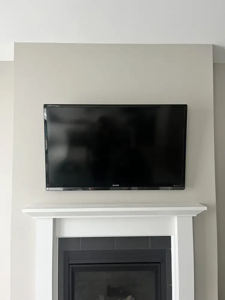 A television mounted on a plain wall above a low white mantel, with no stand and no visible cables.
